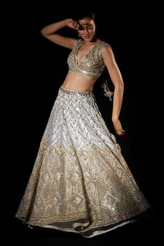 Grey organza lehenga with attached cancan embroidered with mirror and gota work encrusted with water gold zari. Paired with sleeveless embroidered, padded blouse and dupatta.
Component: 3
Pattern: Embroidered
Type Of Work: Geometric
Neckline: V Neck
Sleeve Type: Sleeveless
Fabric: Organza
Color: Grey
Other Details: 
Tassel detail
Scallop dupatta
Geometric motifs
Note: Belt worn by the model is not for sale
Occasion: Sangeet,Bride - Aza Fashions Glamorous Organza Choli With Dupatta, Diwali Hand Embellished Kundan Lehenga, Festive Hand Embellished Sharara For Navratri, Bollywood Hand Embellished Organza Lehenga, Festive Organza Choli With Mirror Work, Gold Hand Embellished Lehenga For Wedding, Hand Embellished Gold Lehenga For Wedding, Hand Embellished Choli For Diwali Reception, Festive Hand Embellished Kundan Lehenga