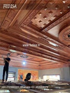 two men working on the ceiling in a room with wood paneling and tile work