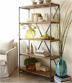 a bookshelf with vases and plants on it next to a couch in a living room