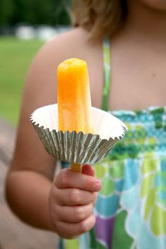 a person holding an orange and white popsicle