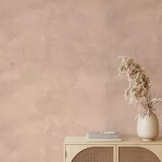 a white vase sitting on top of a wooden cabinet next to a pink painted wall