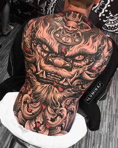 the back of a man's head with tattoos on his arm and shoulder, covered in