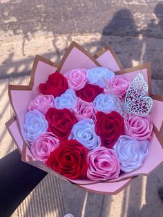 a person holding a bouquet of roses with a butterfly on the top one and two other flowers