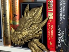 a book shelf with books and a gold dragon head