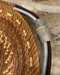 a close up of a basket on the ground with a hose connected to it and another object in the background