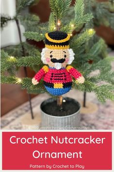 a crochet nutcracker ornament is shown in front of a christmas tree