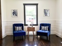 two blue chairs sitting next to each other on a hard wood floor in front of a window