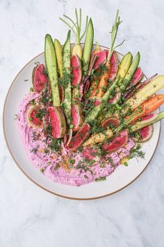 a white plate topped with lots of veggies on top of a pink sauce