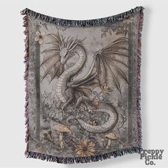 a tapestry with a dragon on it and flowers around the edges, hanging from a wall