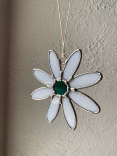 a white and green flower ornament hanging on a wall