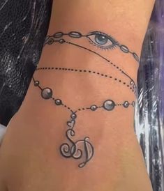 a woman's foot with an eye and chain tattoo on the side of her leg