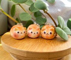 three small ceramic figurines sitting on top of a wooden table next to a potted plant