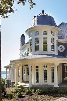 a large white house sitting on top of a lush green field next to the ocean