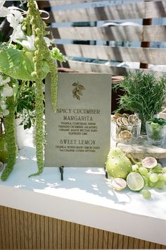 a table topped with lots of different types of flowers and plants next to a sign