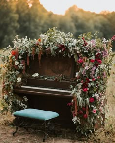 an old piano is adorned with flowers and greenery