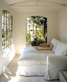 two beds in a room with white walls and windows