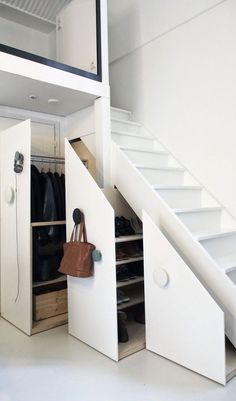 an image of a closet under stairs with shoes and bags on the bottom shelf next to it