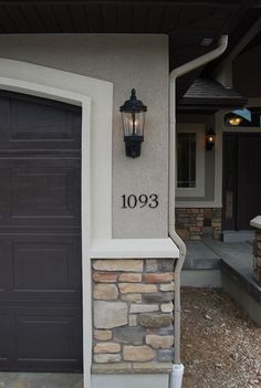 a lamp on the side of a house next to a garage door and entry way