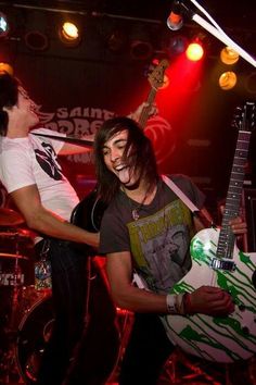 two young men are playing guitars on stage