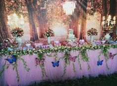 the table is covered with pink tulle and decorated with flowers, vases and butterflies