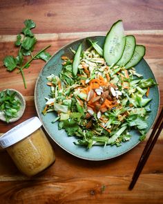 a green plate topped with salad next to a jar of mustard and chopsticks