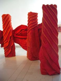 three tall red sculptures sitting on top of a white floor