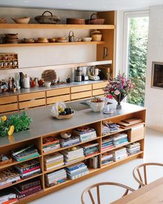 a kitchen with wooden cabinets and shelves filled with books, bowls and plates on top of them