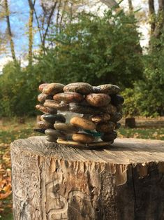 a stack of rocks sitting on top of a wooden stump in front of some trees