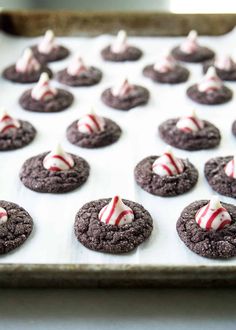 chocolate cookies with white and red candy canes are on a baking sheet, ready to be baked