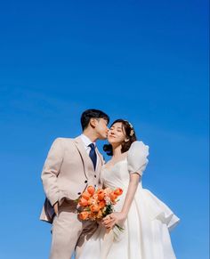 a bride and groom kissing in front of the blue sky on their wedding day,