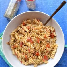 a white bowl filled with pasta on top of a blue table