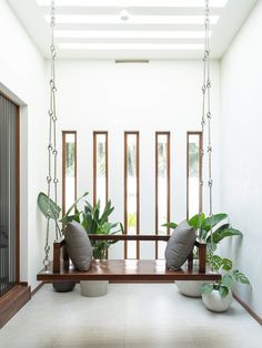 two planters are sitting on a wooden swing in the middle of a white room