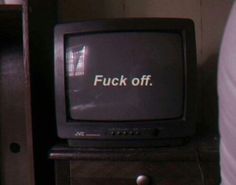 an old television sitting on top of a wooden dresser next to a book shelf with the words f k off written on it