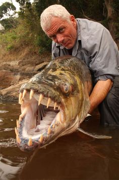 a man holding a large fish with its mouth open