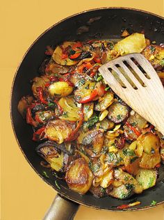 a wooden spatula is being used to stir food in a skillet