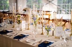 a table set up with place settings and flowers in vases on the tables for an event