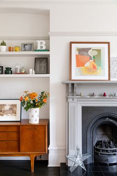 a living room filled with furniture and a fire place in front of a white wall