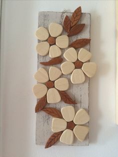 wooden flowers are arranged on a piece of wood with some leaves hanging from it's sides