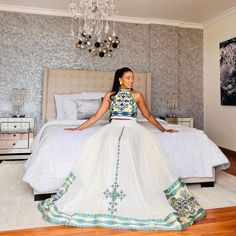 a woman sitting on top of a bed in a bedroom next to a chandelier