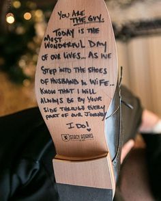 a wooden shoe with writing on it and someone's feet in the background,