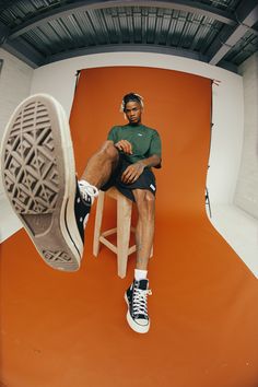 a man sitting on top of a stool with his feet up in the air while wearing headphones