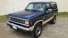 a blue pick up truck parked on top of a gravel road next to a building