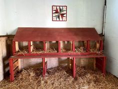 a red bench sitting inside of a barn filled with hay