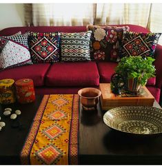 a living room with a red couch and colorful pillows on top of the couches