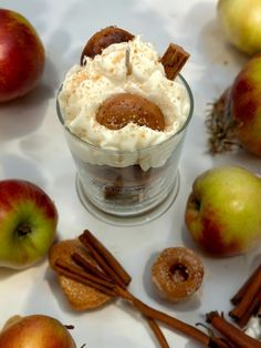 an apple dessert in a glass surrounded by cinnamon sticks and apples