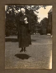 an old black and white photo of a woman standing in the grass