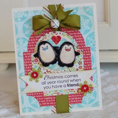 a card with two penguins on it and a green ribbon around the edge that says, christmas comes all year round when you have a friend