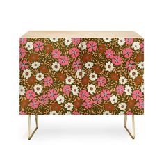 an orange and pink flowered cabinet with gold legs, on a white background that is also part of the furniture collection