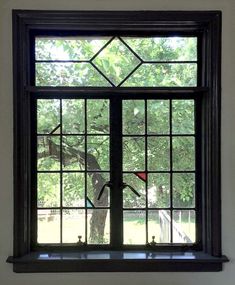 a window that has a bird in the middle of it and some trees behind it