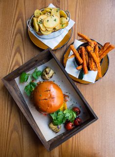 a wooden table topped with two trays filled with food